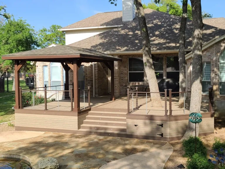 A deck-mounted gazebo with composite decking and cable railing attached to a brick home.
