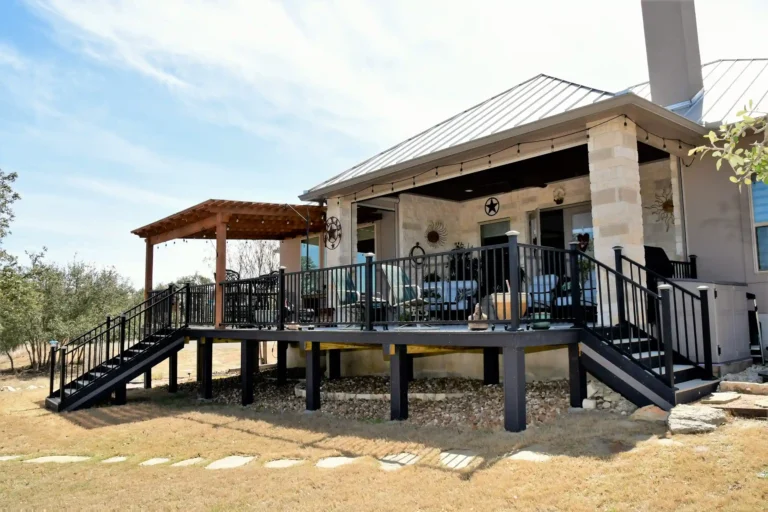Covered porch and raised deck with black railings and outdoor seating at a suburban home.