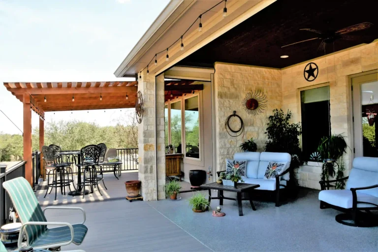 Outdoor porch with seating, potted plants, and a pergola structure overhead.