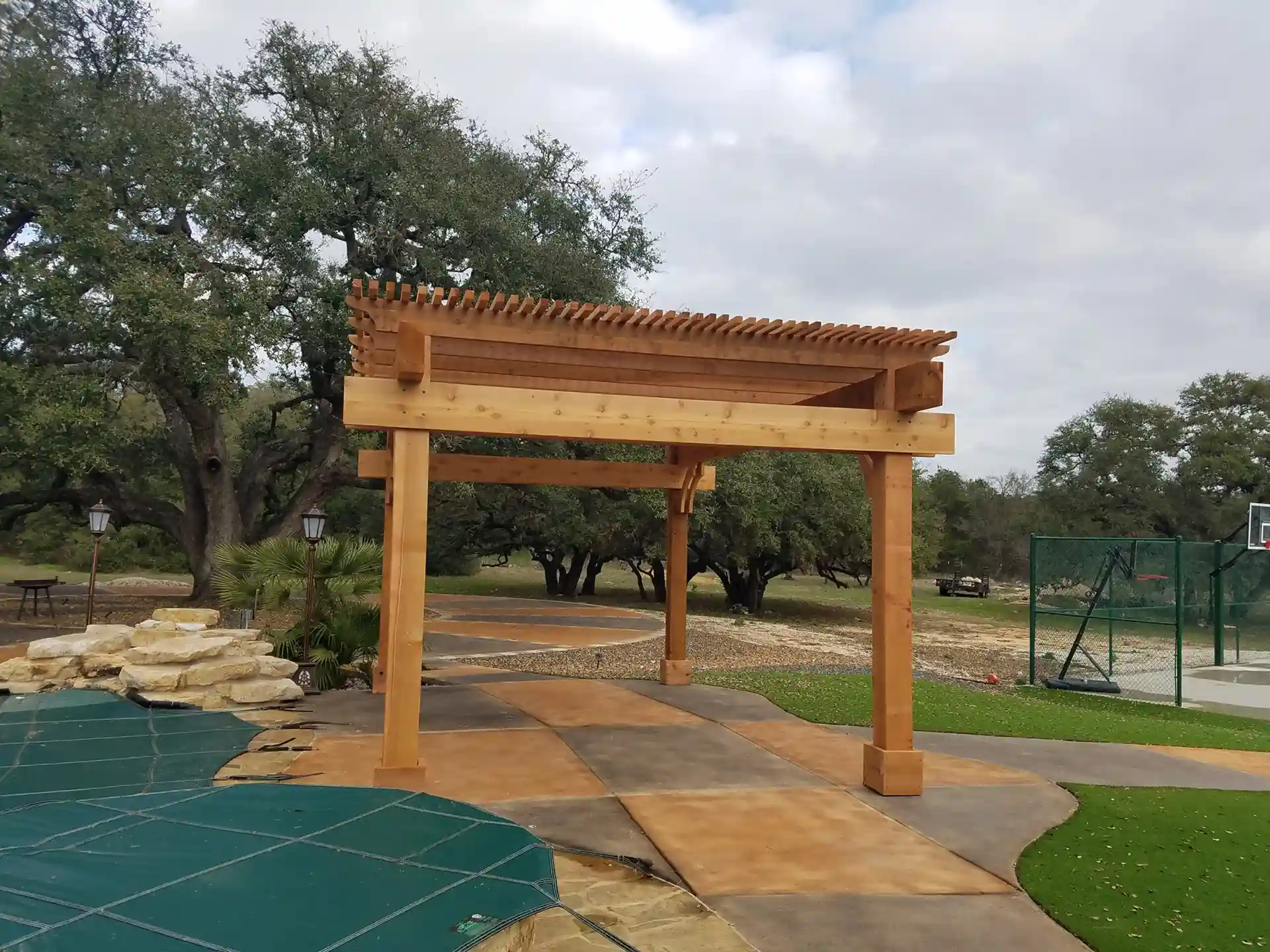 photo of a concrete patio with a traditional wooden pergola