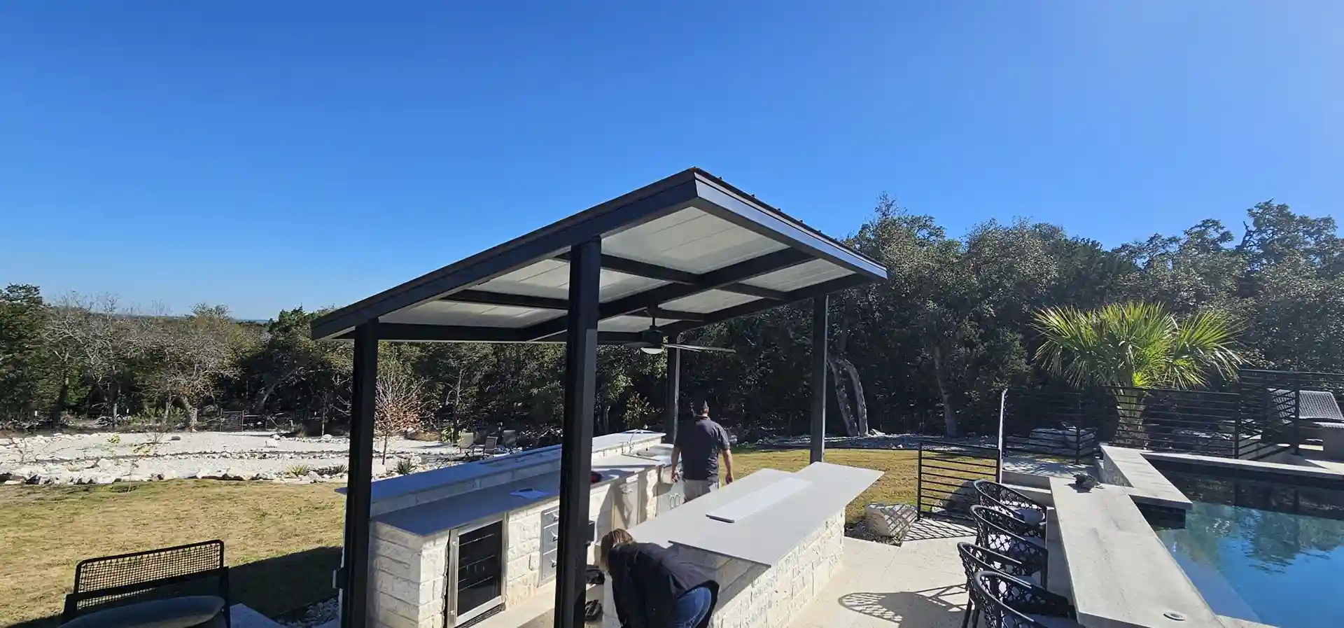 Modern Renaissance Patio Cover with insulated aluminum roof over outdoor kitchen and pool area
