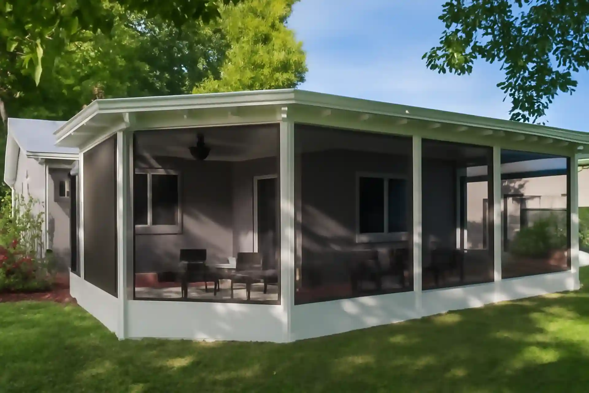 White screened-in porch with patio furniture and ceiling fans, surrounded by green lawn and plants on a sunny day

